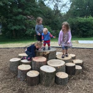 Group of kids playing pieces of wood that BUGG TREE CARE donated to a school in Madison, WI